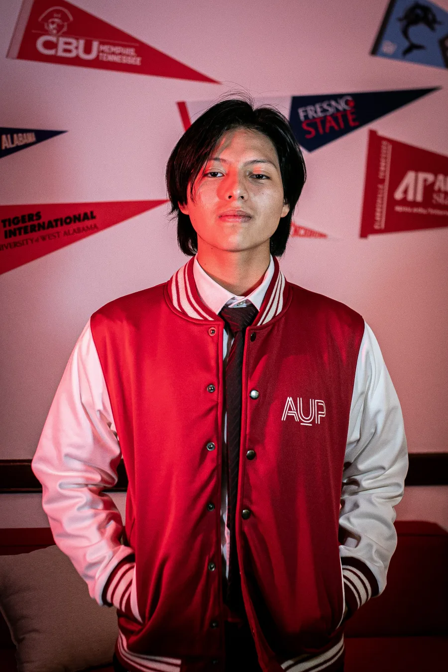 AUP student in front of university pennants