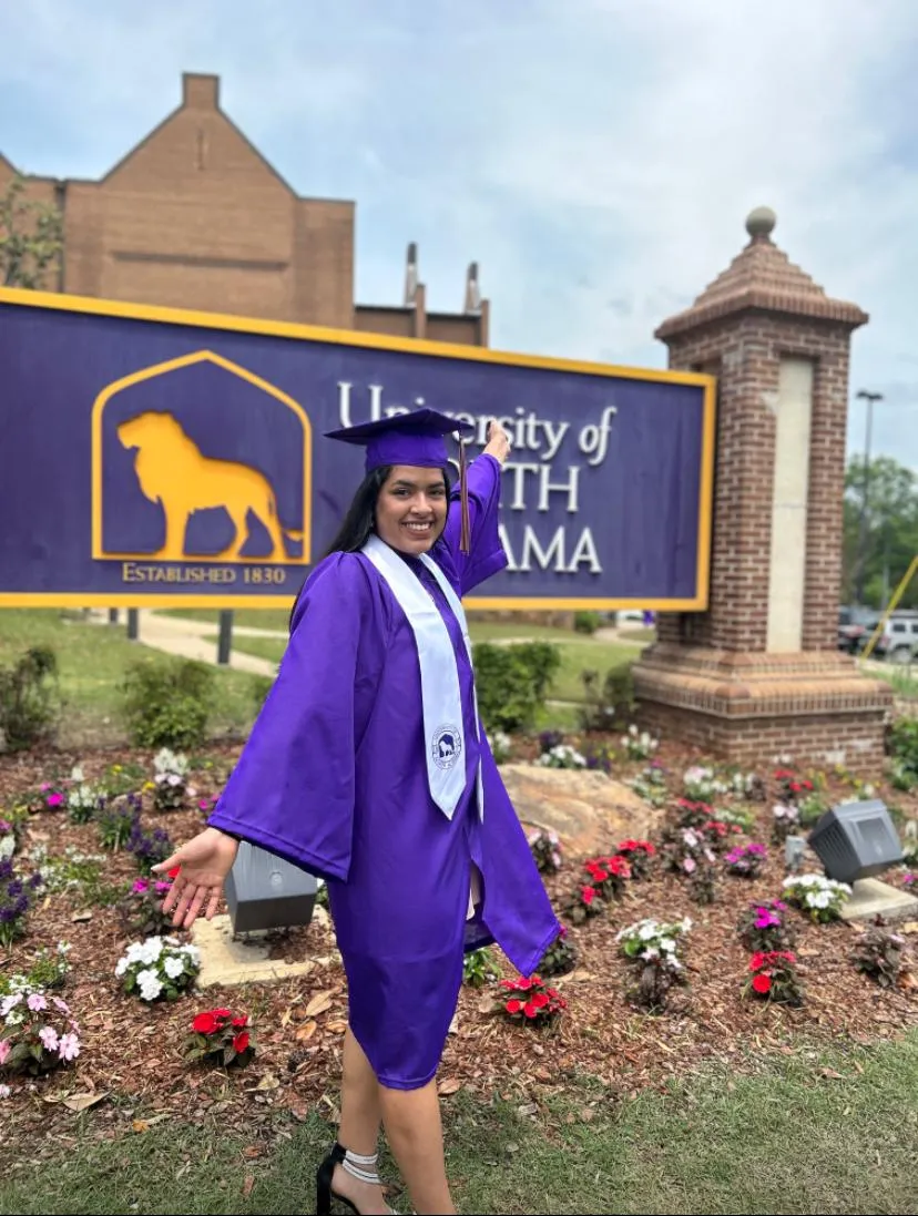 Graduate next to her university sign